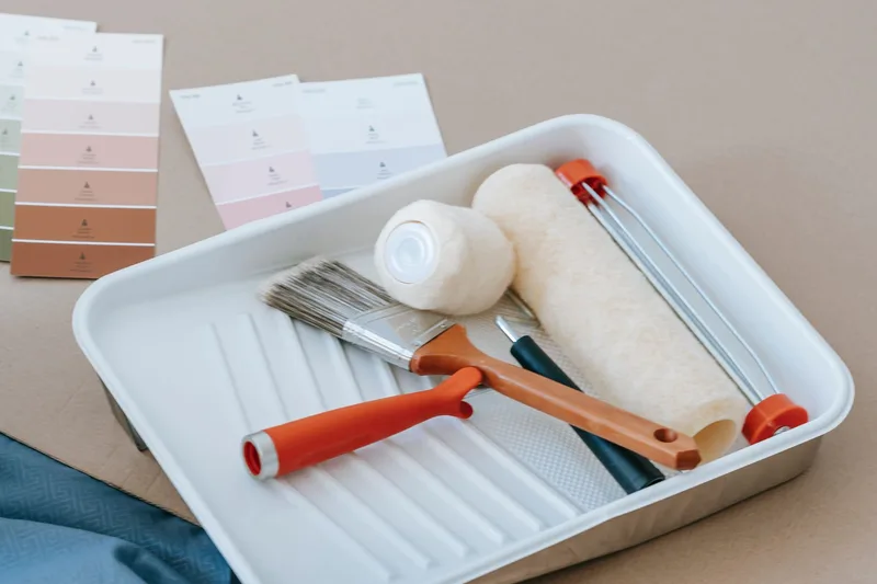 Paint rollers, brushes and colour swatches laid out for a home renovation.